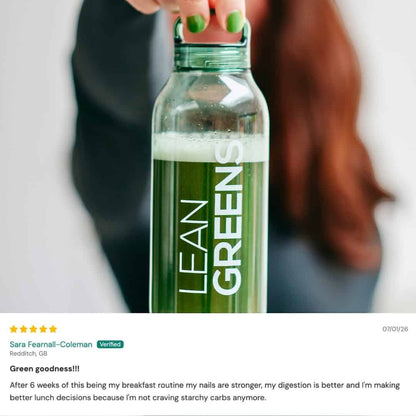 W/Lean Greens super greens powder in a clear bottle with green lid, mixed with water. A daily nutrition supplement.