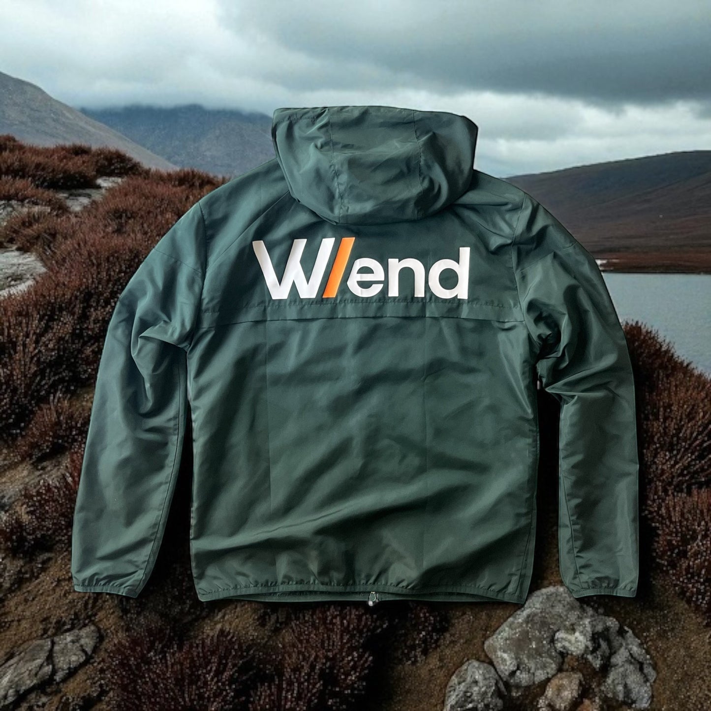 W/end forest green lightweight windbreaker jacket with white logo and orange accent, designed for outdoor movement.